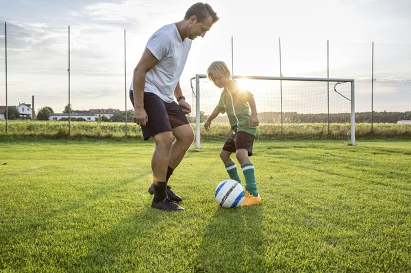 What are the benefits and drawbacks of using synthetic football pitches in training?