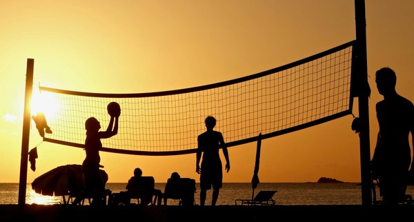 How can beach volleyball players adjust their techniques for different sand conditions?